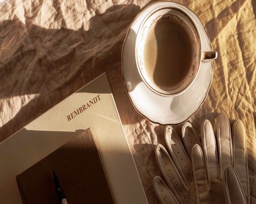 A cup of coffee next to an open notebook in the morning light