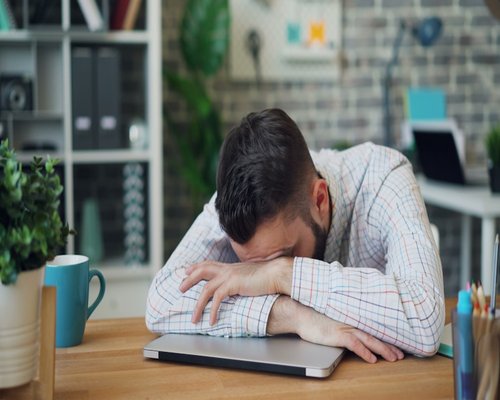 Person working on laptop looking tired, representing daily stress